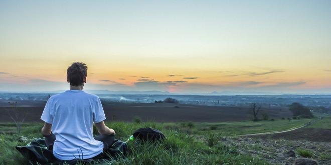 a man calmly watching the sun set over the water