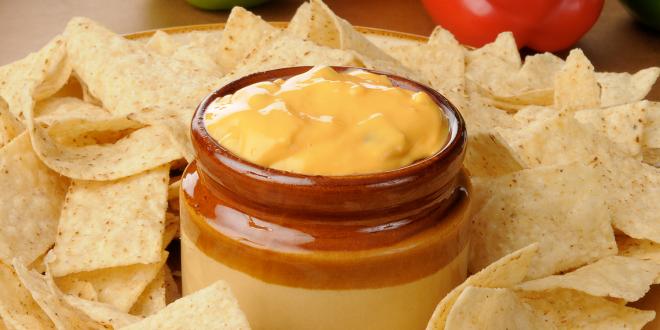 A dip with veggies surrounded by tortilla chips